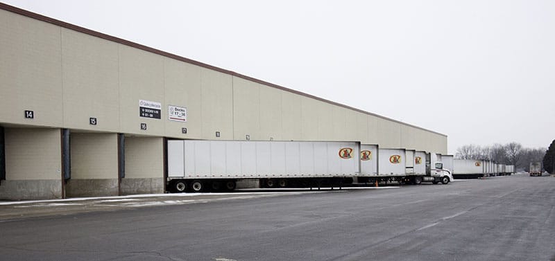 Several transport trailers parked at loading docks outside of a recycling facility.