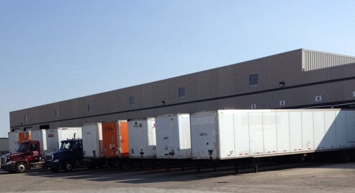 Large grey building with multiple trailers parked at loading docks.