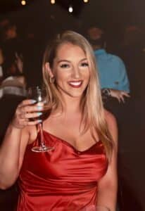 Hannah Hauk in red dress holding a glass of wine