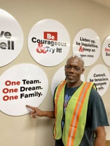 picture of Michael Beal in Quincy Recycle office next to One Team, One Dream, One Family core value sign.